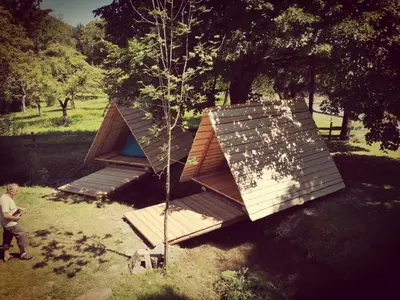 a man standing next to a tree with a house at Kamp na Otoku - Ljubno ob Savinji in Ljubno