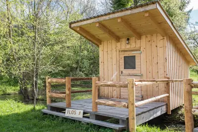 a wooden out house with a porch and a tv at Kamp na Otoku - Ljubno ob Savinji in Ljubno