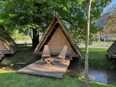 two chairs sitting on a wooden deck in front of a tent at Kamp na Otoku - Ljubno ob Savinji in Ljubno