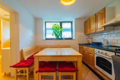 a kitchen with a wooden table and red cushioned chairs at Stol Apartments in Žirovnica