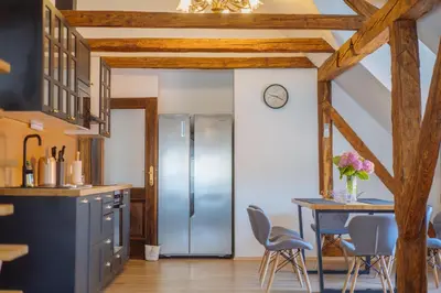 a kitchen with a refrigerator and a table with chairs at Stol Apartments in Žirovnica