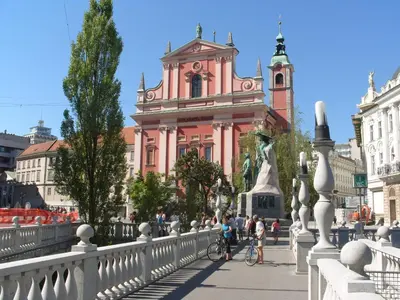 a pink building with a clock tower on a bridge at Studio EMMA Ljubljana - FREE parking, AC, Wifi in Ljubljana