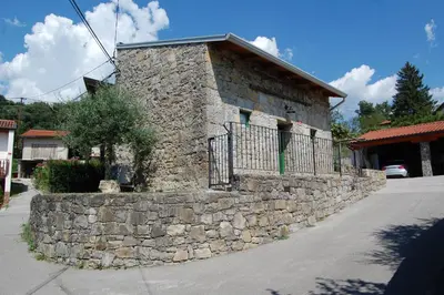 a stone wall next to a building with a gate at Apartma HIŠKA in Dobravlje