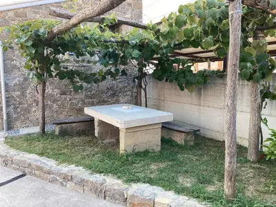 a picnic table and two benches in front of a building at Apartma HIŠKA in Dobravlje