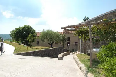 a house with a stone wall next to a sidewalk at Apartma HIŠKA in Dobravlje