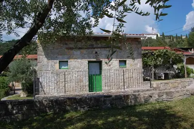 a stone house with a green door at Apartma HIŠKA in Dobravlje