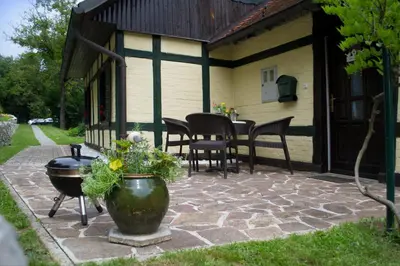 a patio with a grill and a table and chairs at Hiška ob potoku in Dobrna