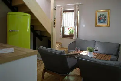 a living room with a table and a green refrigerator at Hiška ob potoku in Dobrna