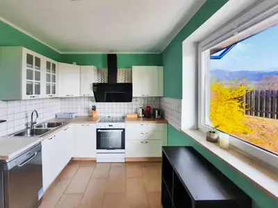 a kitchen with green walls and white cabinets and a window at Deerwood-2-Storey Garden Apartment with Castle view Balcony in Bled