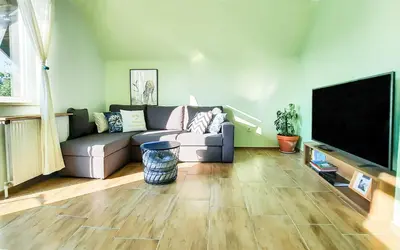 a living room with a couch and a flat screen tv at Deerwood-2-Storey Garden Apartment with Castle view Balcony in Bled