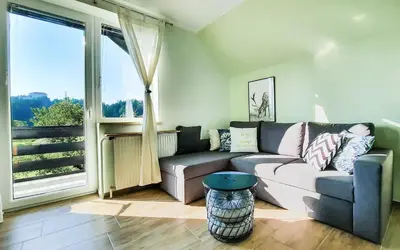 a living room with a couch and a large window at Deerwood-2-Storey Garden Apartment with Castle view Balcony in Bled