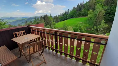 a wooden table and chair on a balcony with a view at Healing Farm in Gorenja Vas