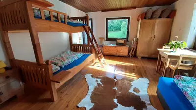 a bedroom with bunk beds and a dining room with a table at Healing Farm in Gorenja Vas