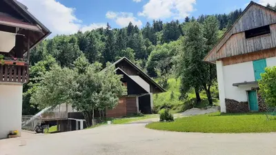 a group of buildings with trees in the background at Healing Farm in Gorenja Vas