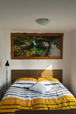 a painting hanging on a wall above a bed at Zemva Stays - JT Apartma, free bikes, big garden with terrace in Bled