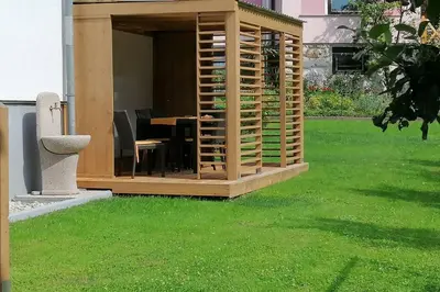 a wooden gazebo in a yard with green grass at Zemva Stays - JT Apartma, free bikes, big garden with terrace in Bled