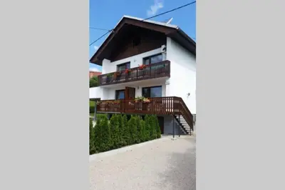 a white house with a balcony and a staircase at Zemva Stays - JT Apartma, free bikes, big garden with terrace in Bled