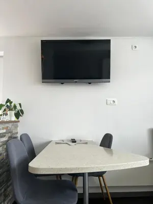 a table with chairs and a television on a wall at Zemva Stays - JT Apartma, free bikes, big garden with terrace in Bled