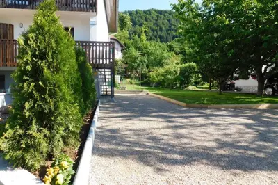a driveway of a house with a gate and trees at Zemva Stays - JT Apartma, free bikes, big garden with terrace in Bled