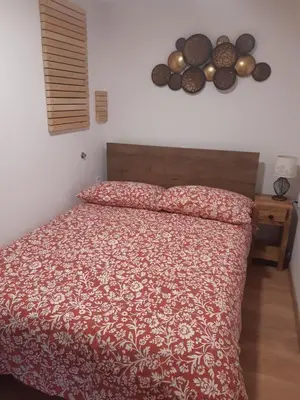 a bedroom with a bed with a red comforter at Apartma LUPIS in Podvolovljek