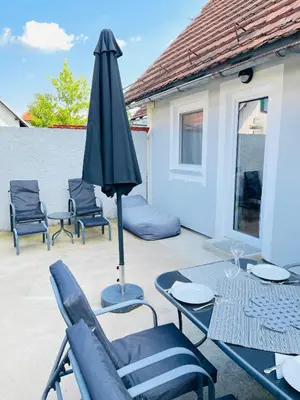 a patio with a table and an umbrella and chairs at Hiška Orel Terme Čatež in Čatež ob Savi