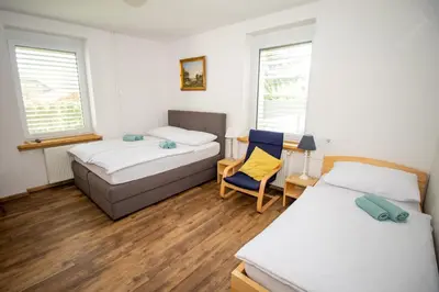 a room with two beds and a chair and two windows at Vila Eva Lesce - Bled in Lesce