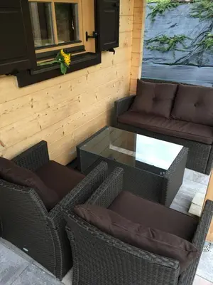 a patio with wicker chairs and a glass table at Loghouse Brunka - Escape from life on a highway in Gornja Radgona