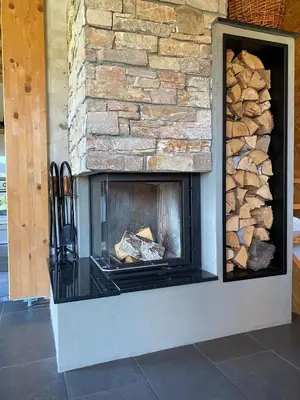 a fireplace with a stone wall with logs in it at Loghouse Brunka - Escape from life on a highway in Gornja Radgona