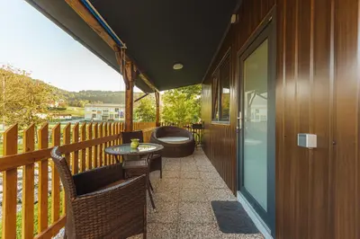 a balcony with a tub and a table and chairs at Holiday Homes I&G by the river next to Olimje in Kozje