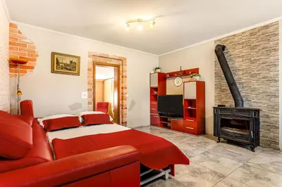 a bedroom with a red bed and a fireplace at Holiday Homes I&G by the river next to Olimje in Kozje