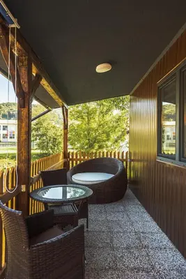 a balcony with two tables and chairs and a tub at Holiday Homes I&G by the river next to Olimje in Kozje