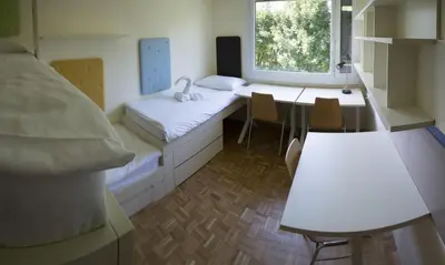 a room with a bed and a table and chairs at Hostel DIC in Ljubljana