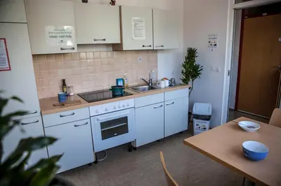 a kitchen with white cabinets and a sink and a table at Hostel DIC in Ljubljana