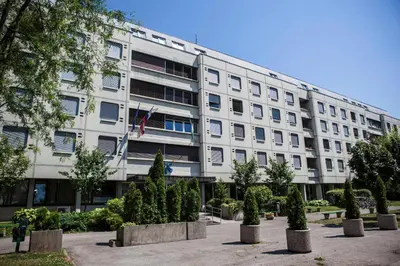 a large white building with trees in front of it at Hostel DIC in Ljubljana