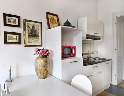 a white kitchen with a vase with flowers on a table at Apartments Katrca Ljubljana in Ljubljana