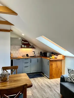 an attic kitchen with a couch and a table at BeeWood apartment in Križe