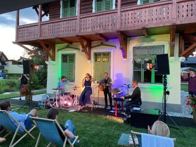 a group of people playing music in a yard at Villa Ruska dača in Ljubljana