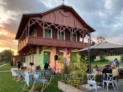a group of people sitting at tables in front of a house at Villa Ruska dača in Ljubljana