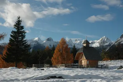 a small chapel in the snow with mountains in the background at Fairytale Cottage - Peaceful Getaway Near Bled in Zgornje Gorje