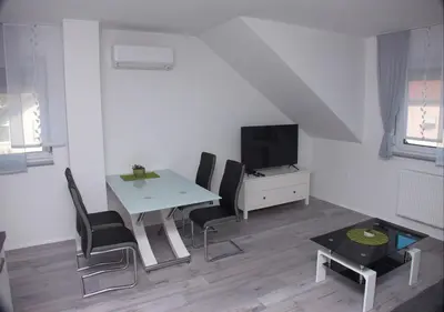 a white living room with a table and a tv at Apartmaji Anita in Begunje pri Cerknici