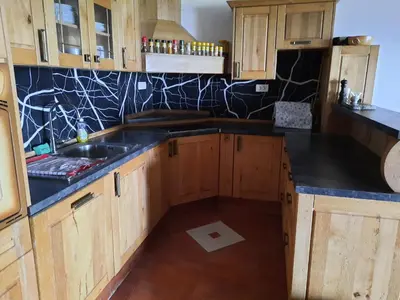 a kitchen with wooden cabinets and a black counter top at Country House Zemljanka in Šentrupert