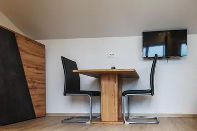 a table with two chairs and a television on a wall at APARTMAJI GORENC in Bled