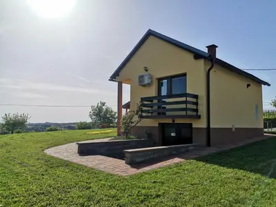 a house on a grassy field with the sun behind it at Počitniška hiša Pavlek in Ivanjkovci