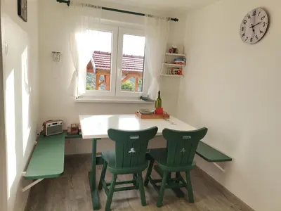 a kitchen with a table and two green chairs at Počitniška hiša Pavlek in Ivanjkovci