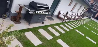 a grill in a backyard with chairs and a lawn at Hiša stare mame in Kamnik