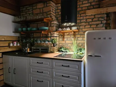 a kitchen with a refrigerator and a brick wall at Hiša stare mame in Kamnik