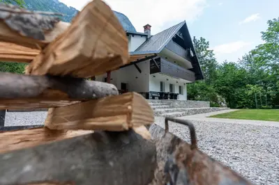 a house behind a fence with a house in the background at Holiday House Destina - Lake Bohinj in Bohinj