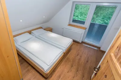 a small bedroom with a bed and two windows at Holiday House Destina - Lake Bohinj in Bohinj