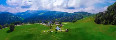an aerial view of a large green field with mountains at Wooden Chalet - Homestead Vrhovc in Železniki