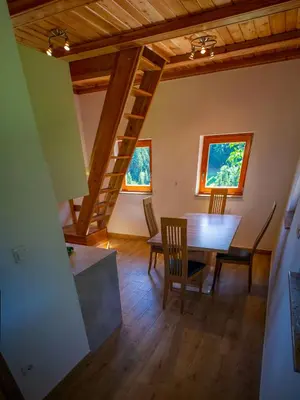 a dining room with a table and chairs and two windows at Wooden Chalet - Homestead Vrhovc in Železniki